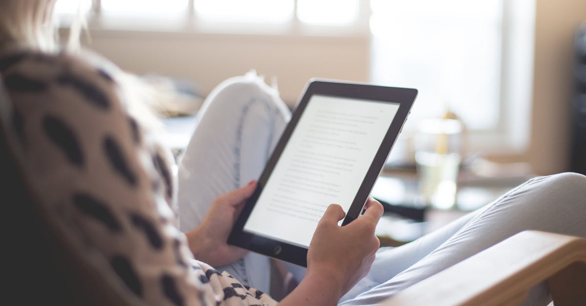 A woman enjoys reading on a tablet, sitting comfortably in a modern living room.